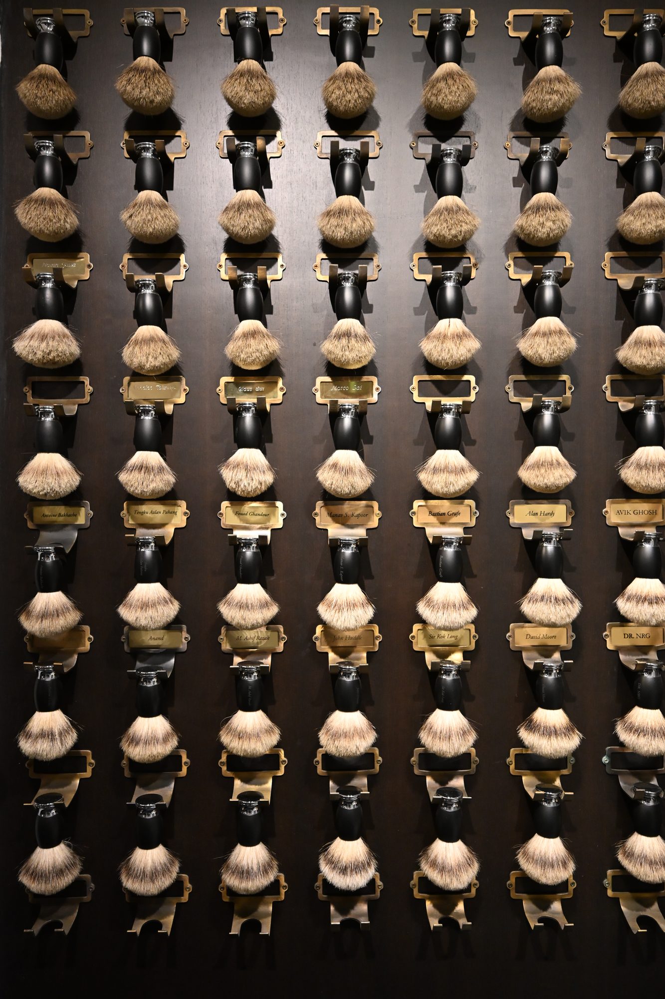 The members' brush wall — badger brushes under brass nameplates